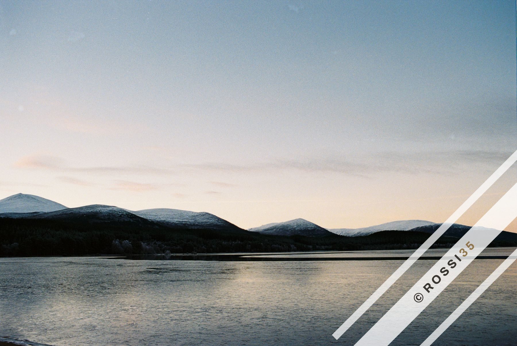 Loch and snow-dusted hills at dusk
